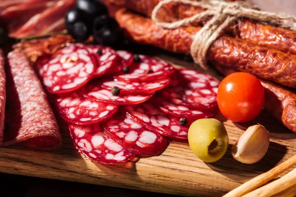 Close up view of wooden cutting boards with delicious smoked sausages, vegetables and sliced salami — Stock Photo