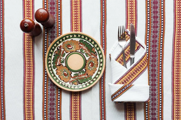 Vista superior da configuração de mesa tradicional com placa ornamentada na toalha de mesa bordada — Fotografia de Stock