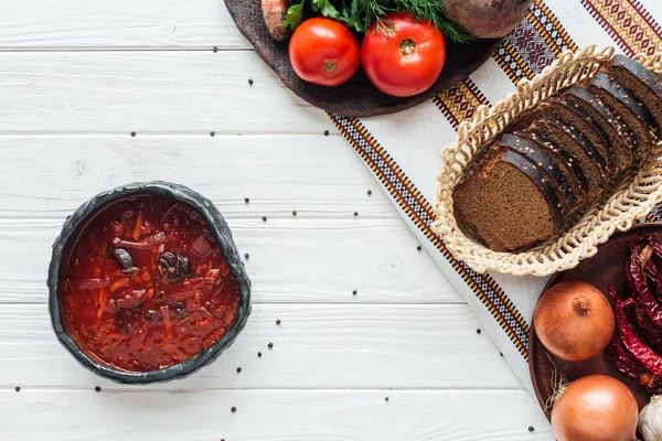 Top view of traditional beetroot soup with ingredients and allspice on white wooden background — Stock Photo