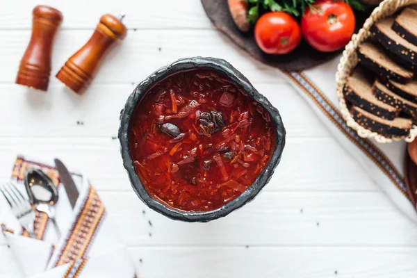 Foco seletivo da sopa tradicional de beterraba com ingredientes em torno de fundo de madeira branca — Fotografia de Stock