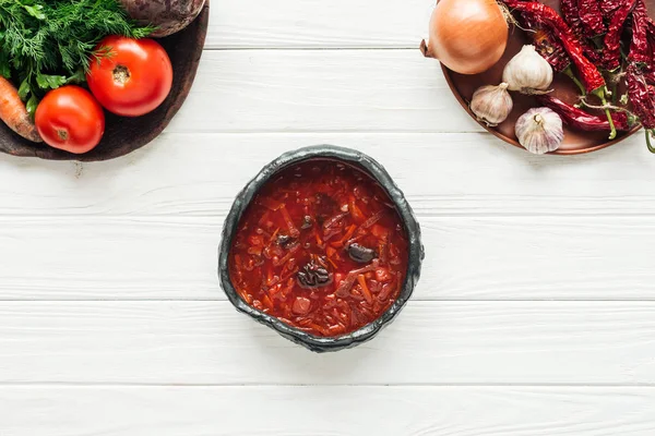 Top view of traditional beetroot soup with vegetable ingredients on white wooden background — Stock Photo