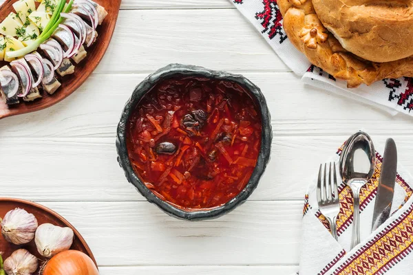 Ansicht der traditionellen Rote-Bete-Suppe mit Besteck und Geschirr auf weißem Holzgrund — Stockfoto