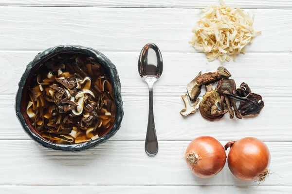 Top view of traditional mushroom soup with spoon and ingredients on white wooden background — Stock Photo