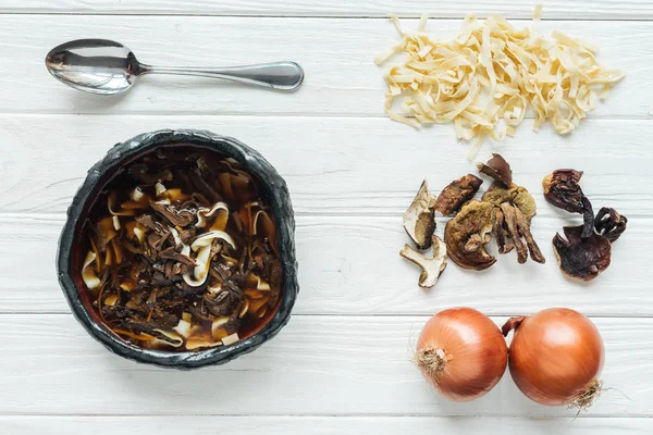 Vue du dessus de la soupe aux champignons traditionnelle avec cuillère et ingrédients sur fond de bois blanc — Photo de stock