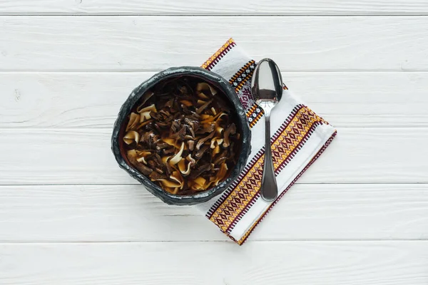 Ansicht der traditionellen Pilzsuppe mit besticktem Handtuch und Löffel auf weißem Holzhintergrund — Stockfoto