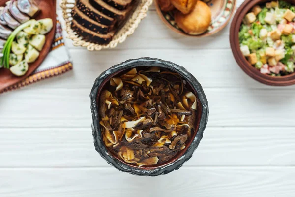 Vista superior de deliciosa sopa de cogumelos tradicional e pratos ao redor em fundo de madeira branca — Fotografia de Stock