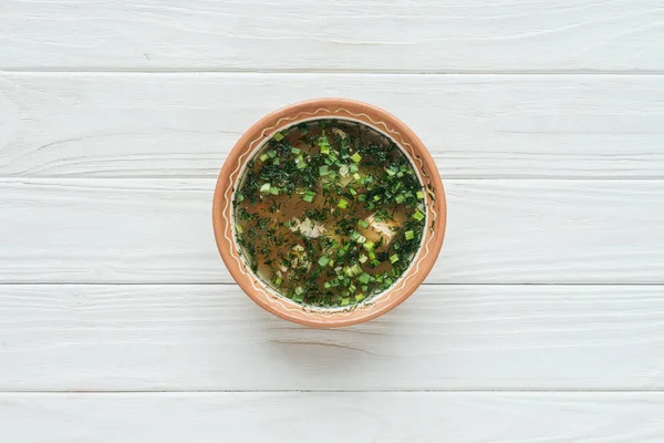 Vista superior de la sabrosa sopa de pescado tradicional con cebolla verde sobre fondo de madera blanca - foto de stock