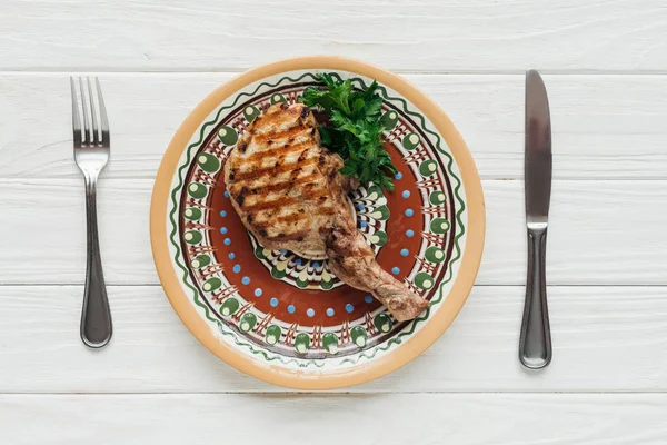 Vista superior de bife de carne de costela no prato com salsa e talheres no fundo de madeira branco — Fotografia de Stock