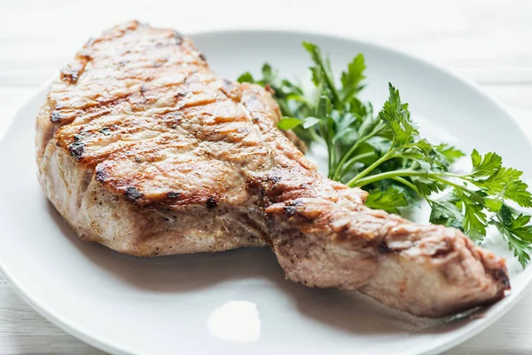 Selective focus of delicious rib eye meat steak on plate with parsley — Stock Photo