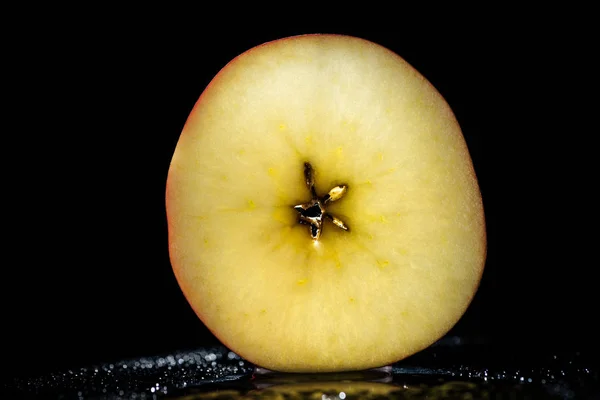 Mitad de manzana madura sobre fondo negro - foto de stock
