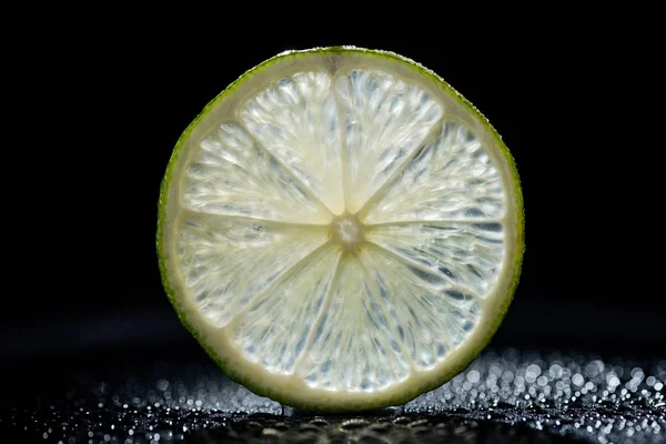 Tranche de citron vert frais sur fond noir — Photo de stock