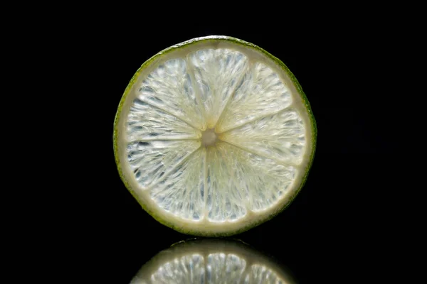 Slice of fresh ripe lime isolated on black — Stock Photo