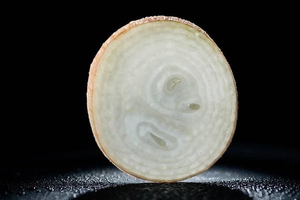 Slice of raw onion with water drops on black background — Stock Photo
