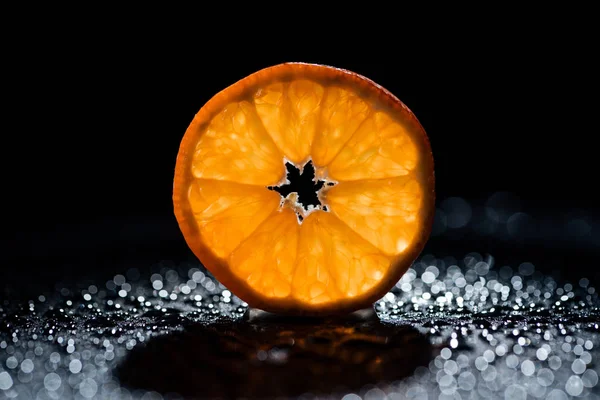 Rebanada de naranja fresca sobre fondo negro con gotas de agua - foto de stock