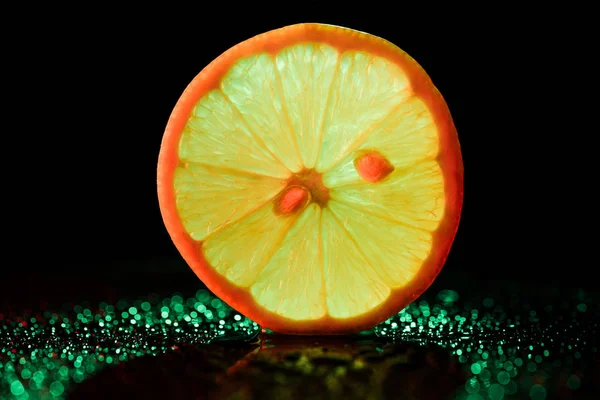 Zitronenscheibe mit Neon-Hintergrundbeleuchtung auf schwarzem Hintergrund — Stockfoto