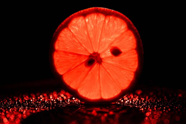 Fatia de toranja no fundo preto com vermelho néon retroiluminado — Fotografia de Stock