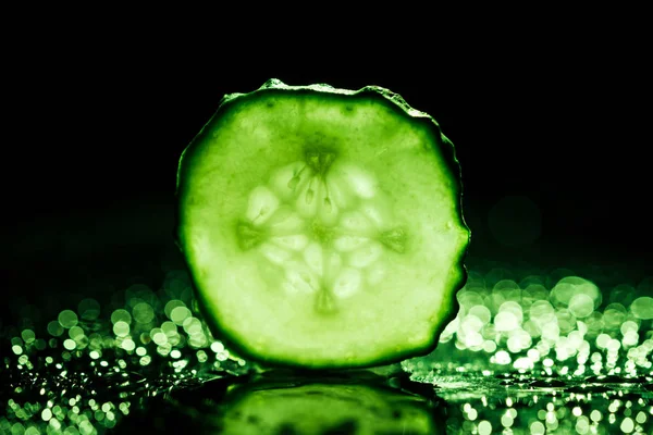 Fetta di cetriolo con retroilluminazione verde su sfondo nero — Foto stock
