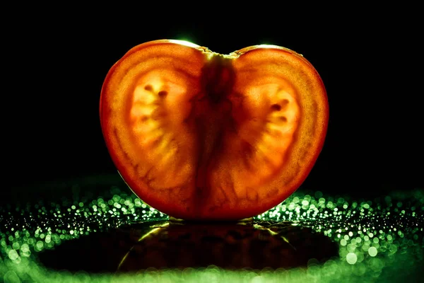 Fatia de tomate fresco com bokeh verde no fundo preto — Fotografia de Stock