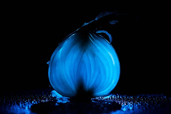 Scheibe rohe Zwiebel mit Wassertropfen und neonblauem Hintergrundlicht auf schwarzem Hintergrund — Stockfoto