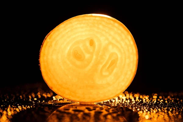 Scheibe rohe Zwiebel mit Wassertropfen und neonorangefarbenem Hintergrundlicht auf schwarzem Hintergrund — Stockfoto