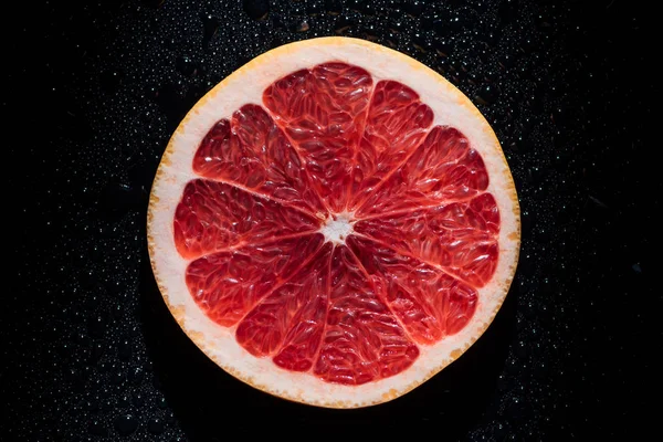 Scheibe Grapefruit auf schwarzem Hintergrund mit Wassertropfen — Stockfoto