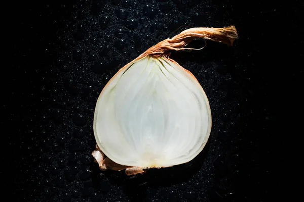 Slice of raw onion with water drops on black background — Stock Photo