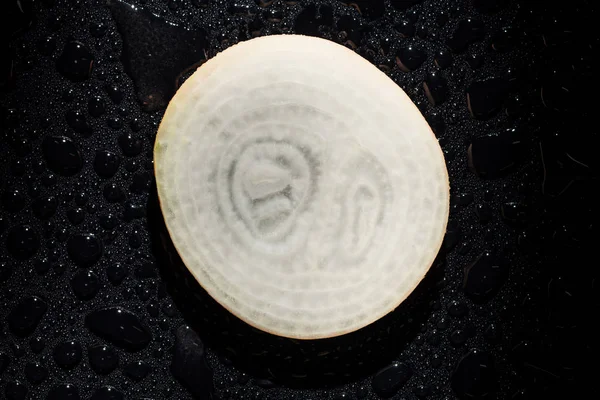 Slice of raw onion with water drops on black background — Stock Photo