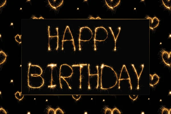 Vista de cerca de letras de luz feliz cumpleaños y corazones en el fondo negro - foto de stock