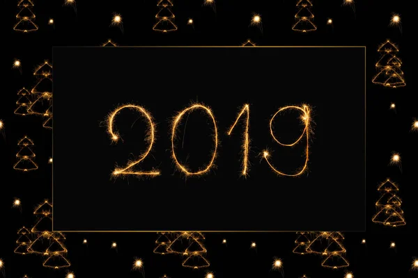 2019 and fir tree light sings on black background — Stock Photo