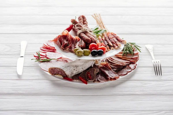 Close up view of delicious meat appetizers with olives and rosemary on white wooden tabletop — Stock Photo