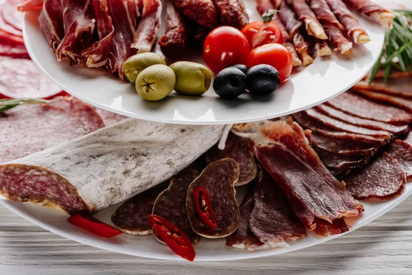 Vista de perto de deliciosos aperitivos de carne com azeitonas em mesa de madeira branca — Fotografia de Stock