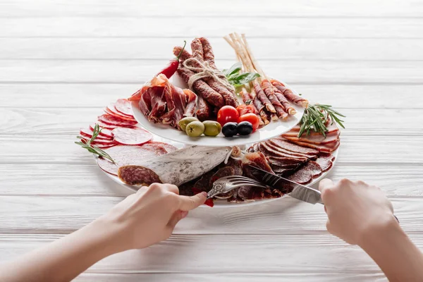 Tiro cortado de mulher tentando aperitivos de carne diferentes na superfície de madeira branca — Fotografia de Stock