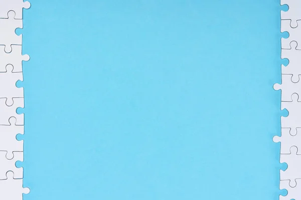 Top view of white puzzle pieces arranged on blue backdrop — Stock Photo