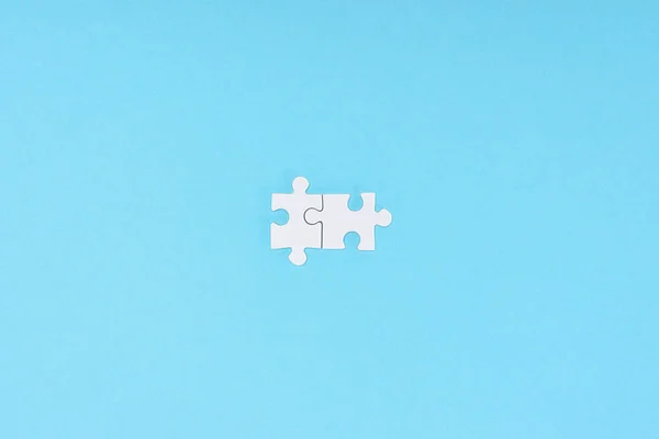 Vista superior de piezas blancas del rompecabezas dispuestas sobre fondo azul - foto de stock