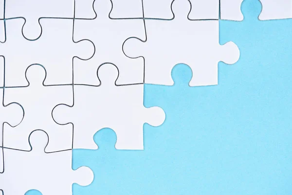 Vue de dessus de l'arrangement des puzzles blancs sur fond bleu — Photo de stock
