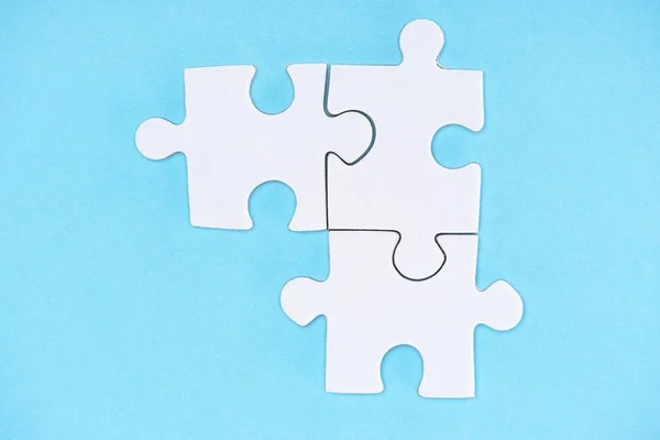 Top view of arranged white puzzle elements on blue backdrop — Stock Photo