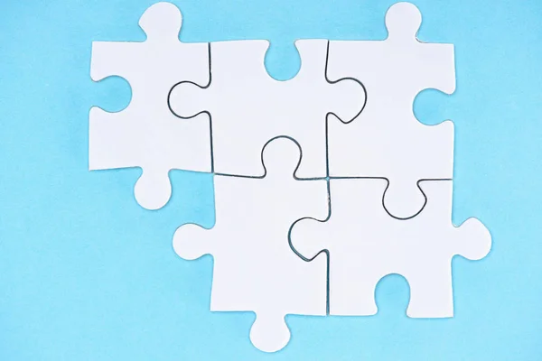 Top view of arranged white puzzle elements on blue backdrop — Stock Photo