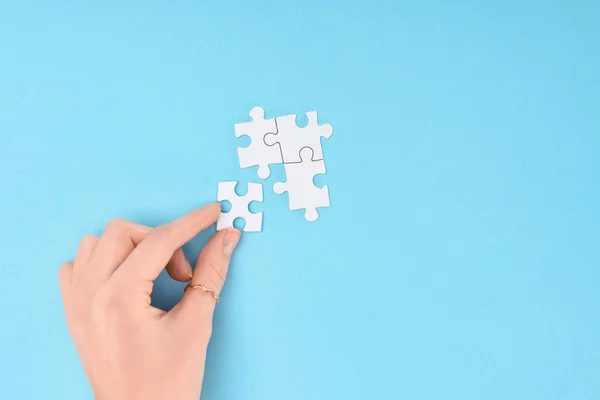 Plan recadré de femme avec des pièces de puzzles blancs sur fond bleu — Photo de stock