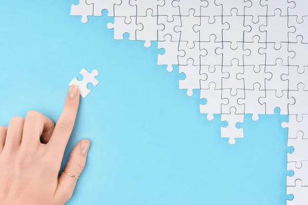 Abgeschnittene Aufnahme einer Frau und weiße Puzzleteile auf blauem Hintergrund — Stockfoto