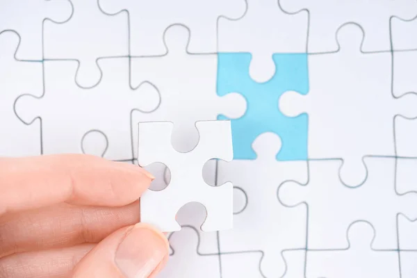 Cropped shot of woman with white puzzles pieces on blue background — Stock Photo