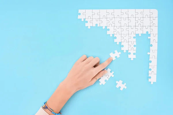 Partial view of woman with white puzzles pieces on blue background — Stock Photo