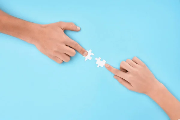 Cropped shot of man and woman with white puzzle pieces on blue backdrop, cooperation concept — Stock Photo