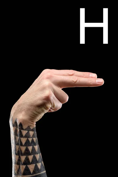 Vista recortada de la mano masculina tatuada que muestra la letra latina - H, lenguaje de signos, aislado en negro - foto de stock