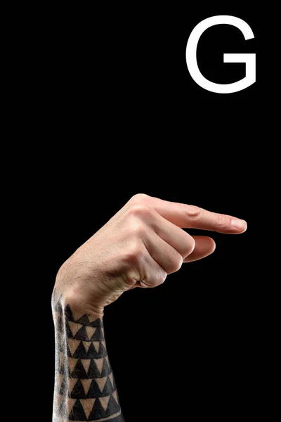 Mano tatuata che mostra lettera latina - G, lingua dei segni, isolata su nero — Foto stock