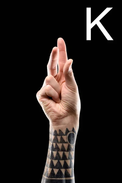 Corte da mão tatuada mostrando letra latina - K, língua de sinais, isolado em preto — Fotografia de Stock