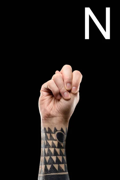 Обрізаний вид татуйованої руки, що показує латинську літеру - N, глуха і тупа мова, ізольована на чорному — стокове фото