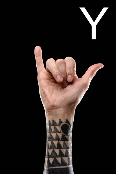 Vista parcial de la mano masculina tatuada mostrando la letra latina - Y, lenguaje sordo y mudo, aislado en negro - foto de stock