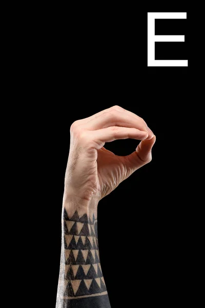 Cropped view of tattooed male hand showing cyrillic letter, deaf and dumb language, isolated on black — Stock Photo