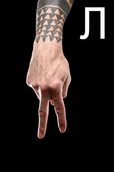 Partial view of tattooed male hand showing cyrillic letter, deaf and dumb language, isolated on black — Stock Photo