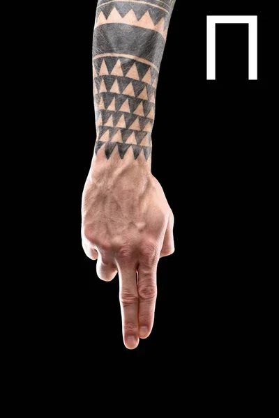 Partial view of tattooed hand showing cyrillic letter, deaf and dumb language, isolated on black — Stock Photo